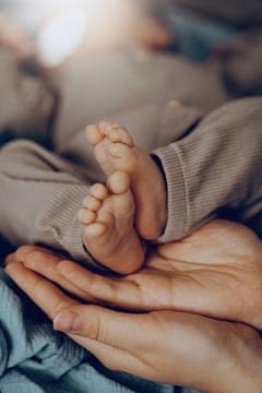A newborn baby's tiny feet cradled in an adult's hands